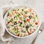 Creamy Greek Yogurt Macaroni Salad in a white bowl with dill, cucumber, red pepper, and creamy pasta