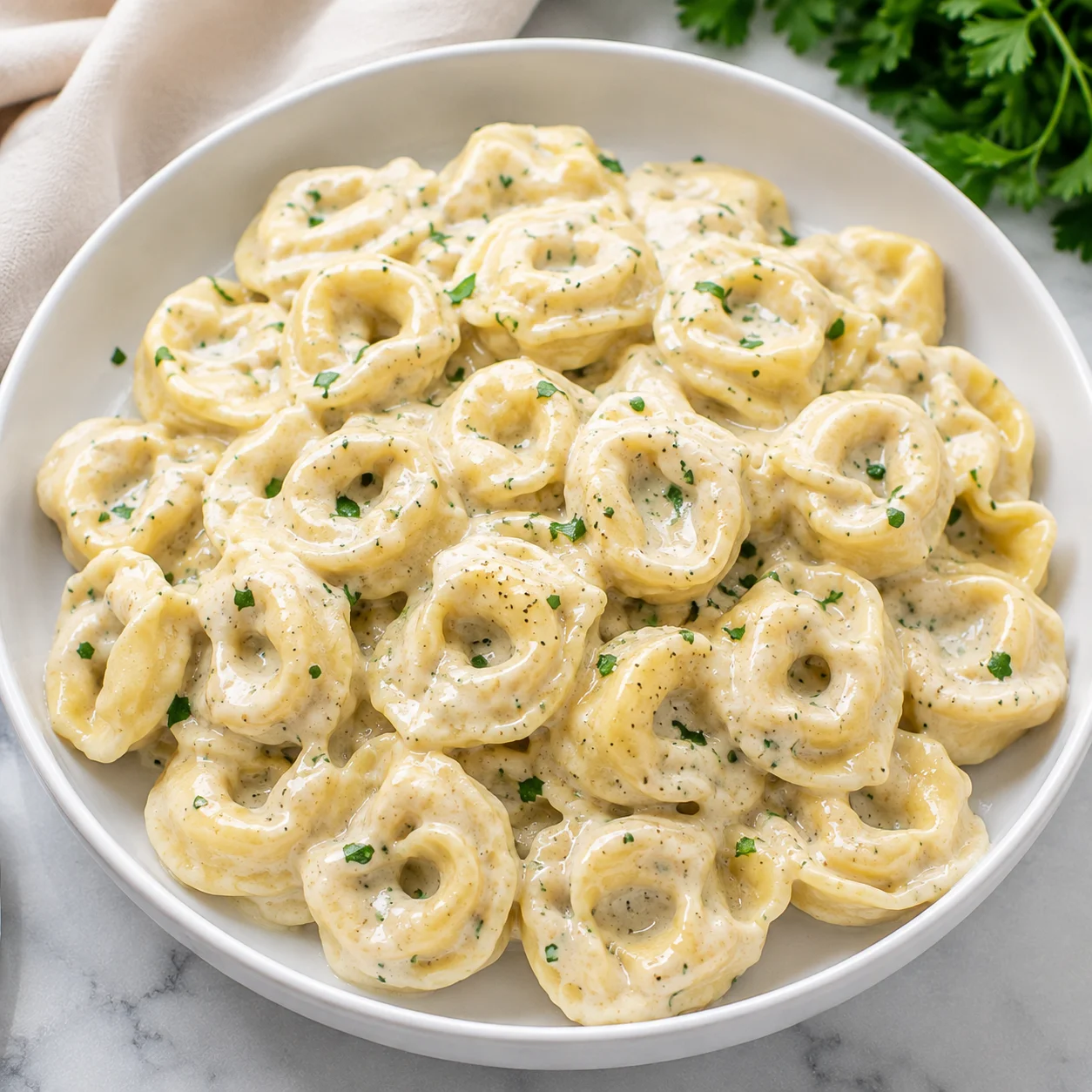 Creamy Tortellini Sauce with golden pasta in glossy cheese sauce on a white plate