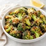 Crispy Parmesan Crusted Broccoli Florets in a white bowl with golden cheese and lemon