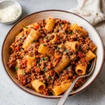 Easy Rigatoni Bolognese with ridged pasta, meaty red sauce, Parmesan, and parsley in a bowl