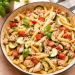 Fresh Chicken Pasta Primavera with golden penne, zucchini, tomatoes, peas, and basil in a skillet