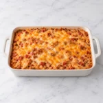 Salsa chicken rice casserole with chicken, rice, salsa, and melted golden cheese in a modern cream ceramic baking dish on a clean white marble surface.