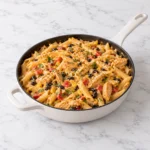 Southwest Chicken Alfredo with creamy penne, seasoned chicken, black beans, corn, and red pepper in a modern cream-colored skillet on a clean white marble surface.